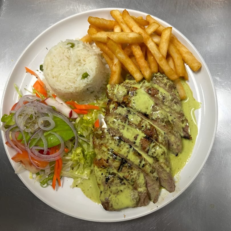Grilled steak with green sauce, white rice, french fries, and a side salad on a white plate.